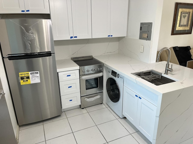 kitchen featuring appliances with stainless steel finishes, a sink, washer / clothes dryer, a peninsula, and white cabinetry