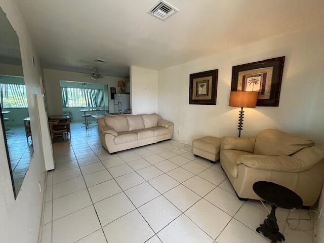 living room featuring a ceiling fan, visible vents, and light tile patterned flooring