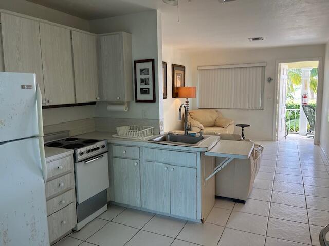 kitchen featuring a sink, light countertops, a peninsula, open floor plan, and white appliances