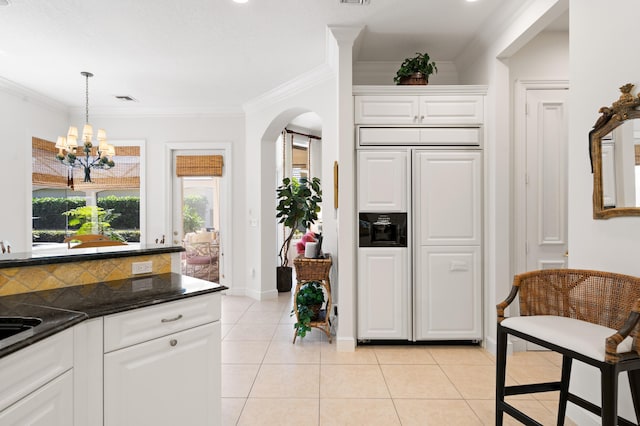 kitchen featuring light tile patterned flooring, arched walkways, paneled fridge, and ornamental molding