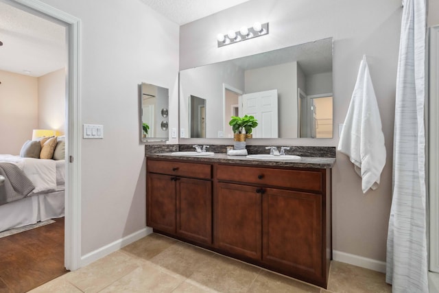 full bath featuring double vanity, ensuite bath, baseboards, and a sink