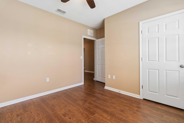 unfurnished bedroom featuring dark wood-style floors, visible vents, and baseboards