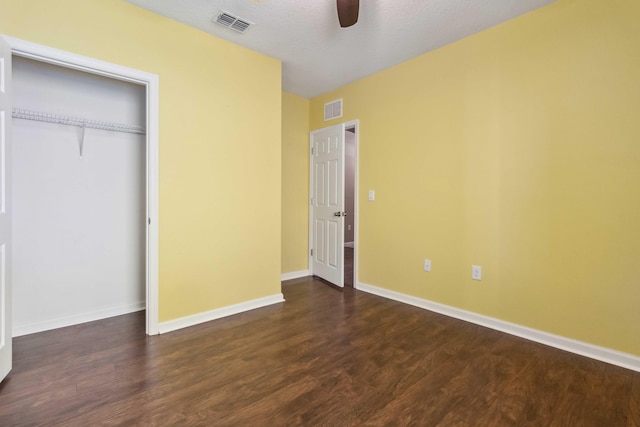 unfurnished bedroom featuring dark wood finished floors, baseboards, visible vents, and a closet