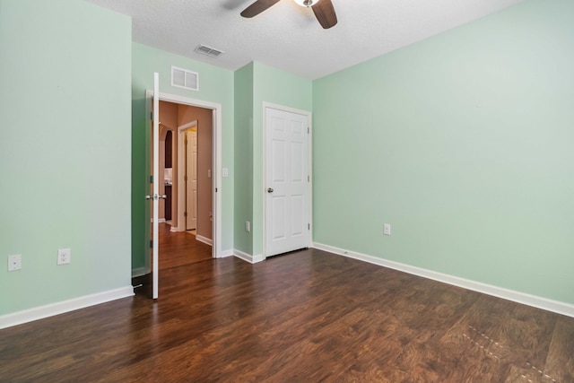 spare room with dark wood finished floors, visible vents, ceiling fan, and baseboards