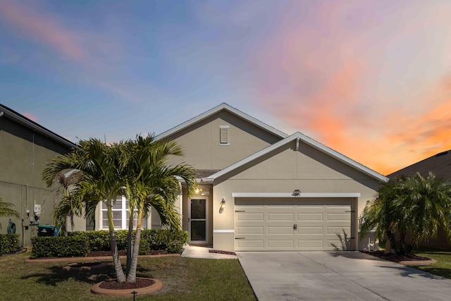 view of front facade with stucco siding, a garage, concrete driveway, and a lawn