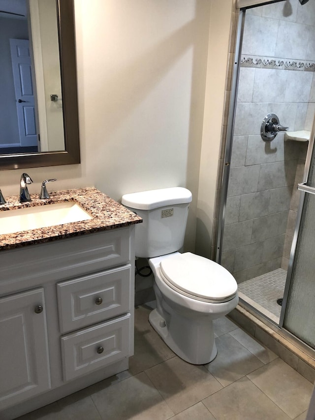 bathroom featuring a stall shower, tile patterned flooring, vanity, and toilet