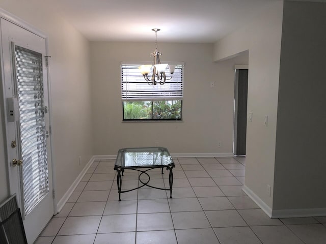 unfurnished dining area with light tile patterned flooring, baseboards, and an inviting chandelier