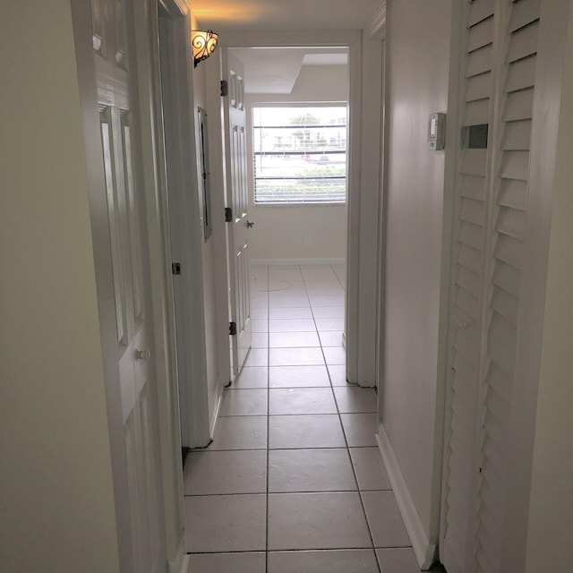 hall featuring baseboards and light tile patterned floors