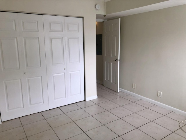 unfurnished bedroom with a closet, baseboards, and light tile patterned floors