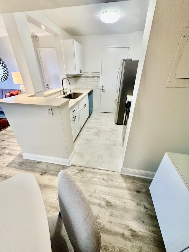 kitchen featuring dishwasher, freestanding refrigerator, marble finish floor, white cabinetry, and a sink