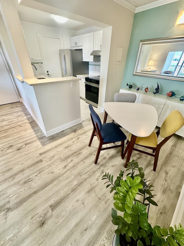 dining room featuring light wood-style flooring and crown molding