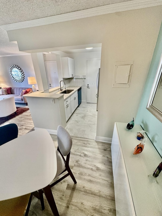 kitchen featuring light wood-style flooring, a sink, light countertops, white cabinetry, and tasteful backsplash