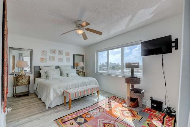 bedroom featuring baseboards, light wood-style floors, ceiling fan, and a textured ceiling