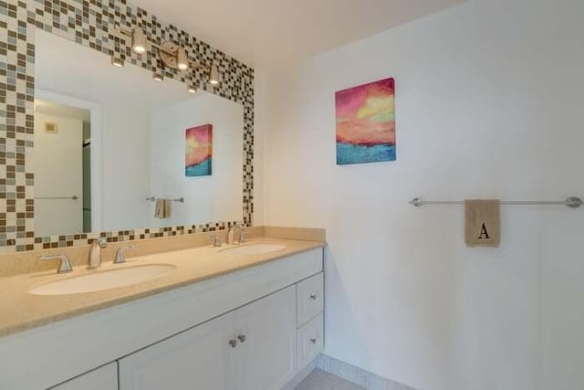 full bath featuring double vanity, tasteful backsplash, and a sink