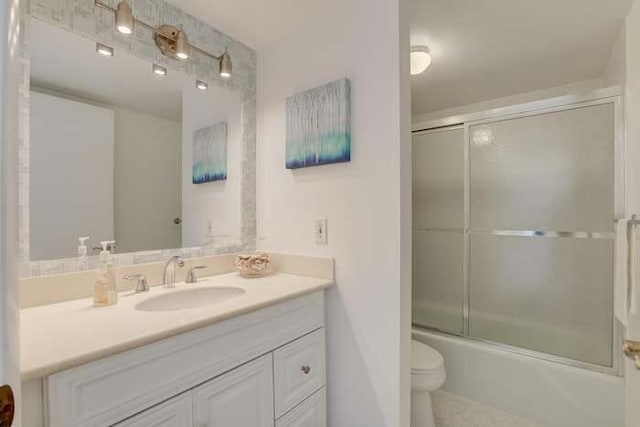 full bath featuring vanity, toilet, and shower / bath combination with glass door