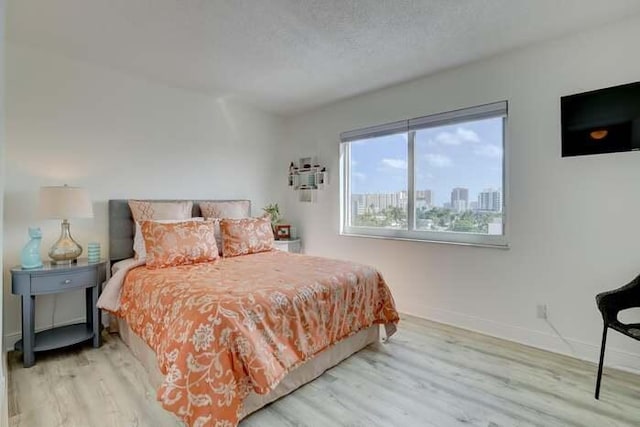 bedroom with wood finished floors, baseboards, and a textured ceiling