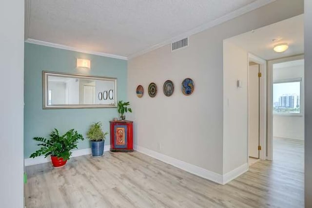 spare room featuring visible vents, crown molding, baseboards, and wood finished floors