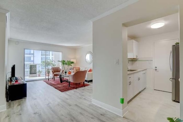 interior space with open floor plan, a textured ceiling, white cabinetry, and freestanding refrigerator