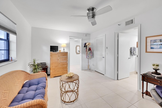 living area featuring light tile patterned floors, visible vents, baseboards, and a ceiling fan