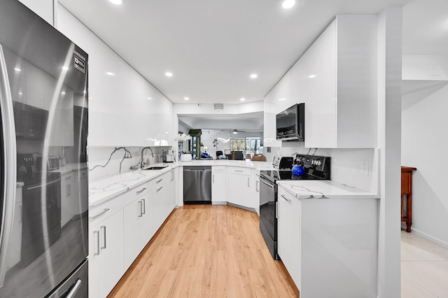 kitchen featuring light stone counters, a sink, black appliances, white cabinets, and modern cabinets