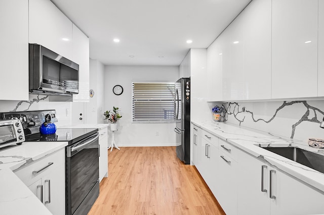 kitchen with a sink, modern cabinets, white cabinetry, and stainless steel appliances