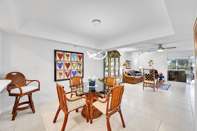 dining area with light tile patterned floors, a raised ceiling, and rail lighting