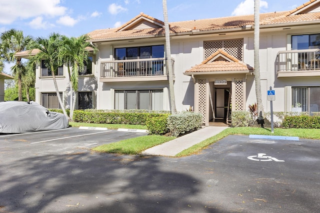 view of front of home featuring uncovered parking, a tiled roof, and stucco siding