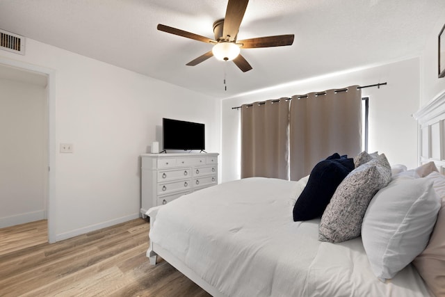 bedroom featuring ceiling fan, light wood-type flooring, visible vents, and baseboards