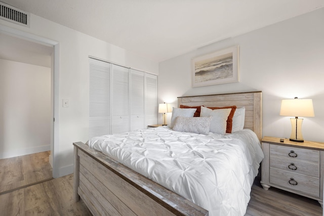 bedroom with baseboards, a closet, visible vents, and wood finished floors