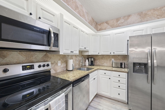 kitchen featuring white cabinetry, appliances with stainless steel finishes, backsplash, and a sink