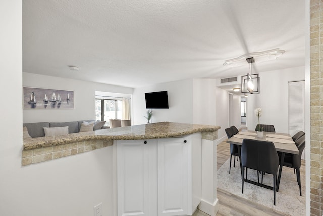 kitchen featuring light wood-style flooring, visible vents, open floor plan, and a textured ceiling