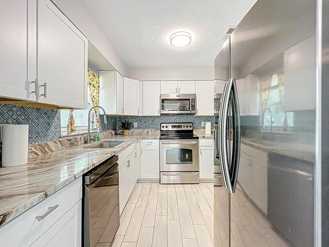1201 Susan St, Leesburg, FL 34748 - kitchen with white cabinetry, light stone countertops, decorative backsplash, stainless steel appliances, and a sink