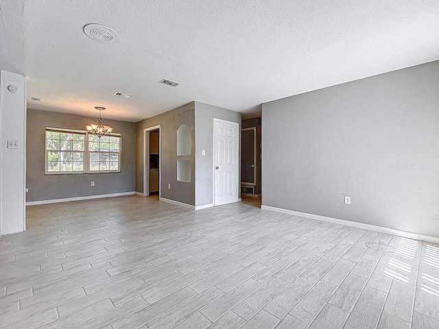 1201 Susan St, Leesburg, FL 34748 - unfurnished living room featuring baseboards, light wood-type flooring, an inviting chandelier, a textured ceiling, and visible vents