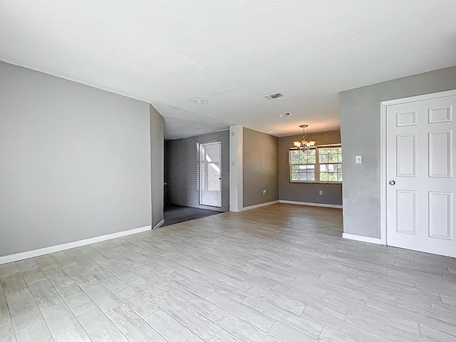 1201 Susan St, Leesburg, FL 34748 - unfurnished living room featuring visible vents, baseboards, light wood-type flooring, and a notable chandelier