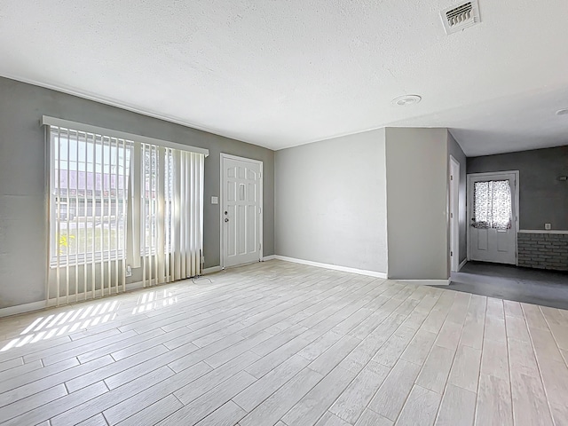 1201 Susan St, Leesburg, FL 34748 - unfurnished living room with light wood-type flooring, baseboards, visible vents, and a textured ceiling