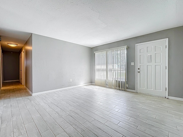1201 Susan St, Leesburg, FL 34748 - unfurnished living room with light wood finished floors, a textured ceiling, and baseboards