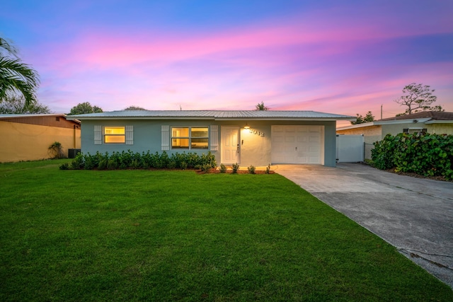 ranch-style house featuring driveway, a garage, fence, a front lawn, and stucco siding