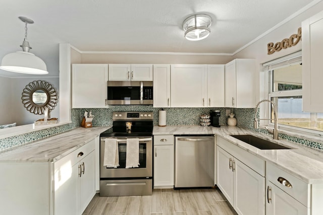 kitchen featuring stainless steel appliances, a peninsula, a sink, white cabinets, and tasteful backsplash