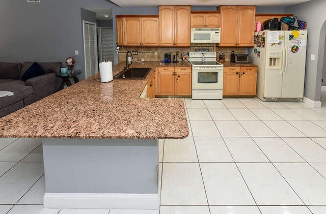 kitchen featuring a sink, light tile patterned flooring, tasteful backsplash, white appliances, and light stone countertops