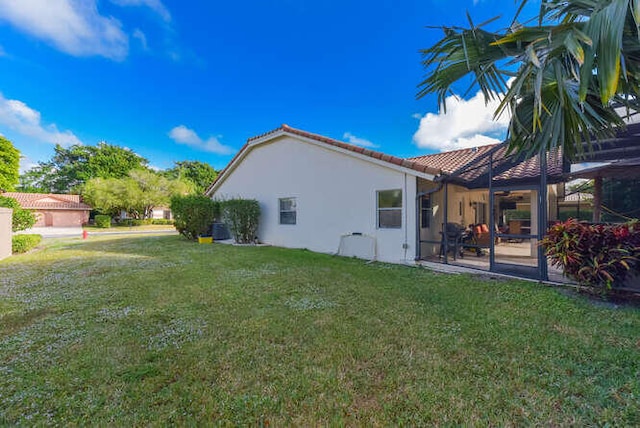 back of house with a tile roof, a lawn, a patio, and stucco siding