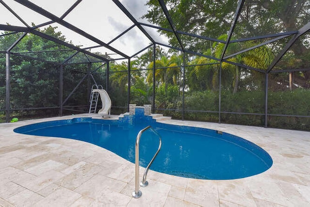 pool with glass enclosure, a water slide, and a patio