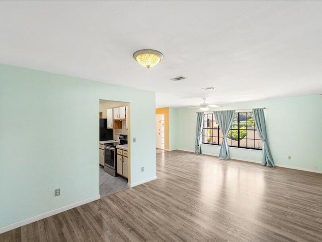 1821 SE Hanby Ave, Port Saint Lucie, FL 34952 - unfurnished living room featuring light wood-style flooring, baseboards, and ceiling fan