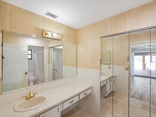 1821 SE Hanby Ave, Port Saint Lucie, FL 34952 - full bathroom featuring wallpapered walls, tile walls, healthy amount of natural light, toilet, and a wainscoted wall