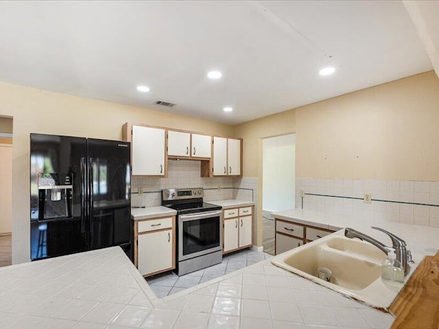 1821 SE Hanby Ave, Port Saint Lucie, FL 34952 - kitchen with black fridge, stainless steel range with electric stovetop, a sink, decorative backsplash, and recessed lighting