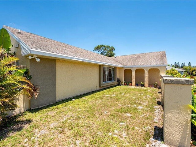 1821 SE Hanby Ave, Port Saint Lucie, FL 34952 - back of house featuring a lawn, stucco siding, and a shingled roof