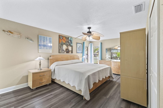 bedroom featuring baseboards, a textured ceiling, visible vents, and dark wood-style flooring