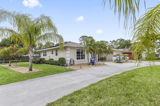 ranch-style house with concrete driveway, a front lawn, fence, and stucco siding