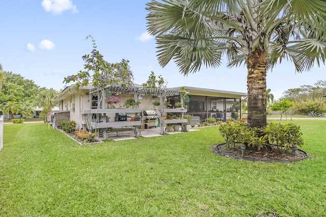 rear view of house with a yard, a patio, and a sunroom