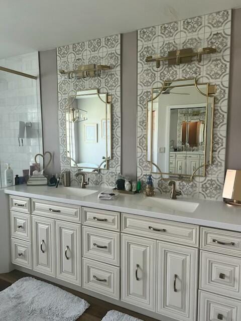 bathroom with double vanity, a tile shower, and a sink