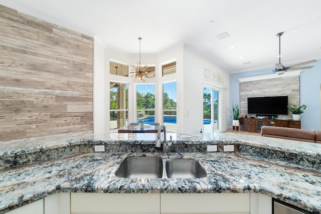 15730 Cedar Grove Ln, Wellington, FL 33414 - kitchen featuring open floor plan, ornamental molding, ceiling fan with notable chandelier, a sink, and stone countertops